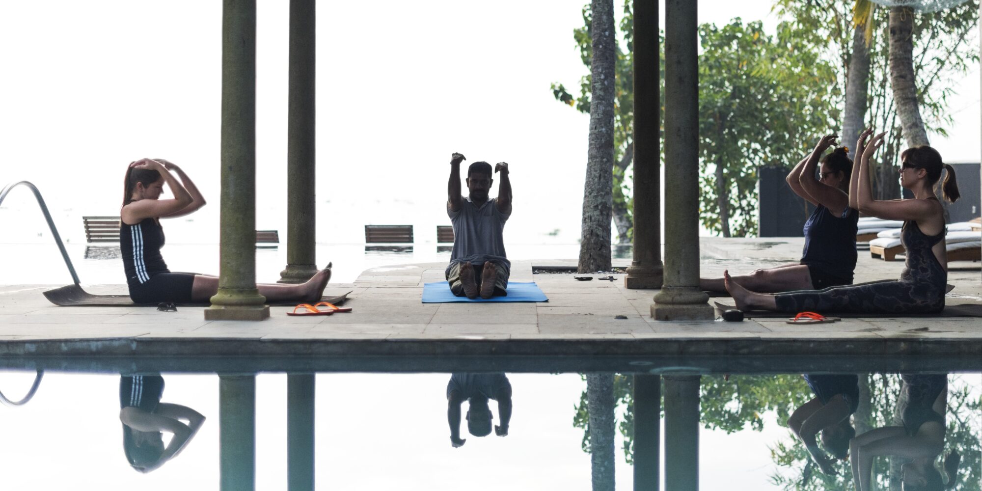 People participating near a pool at Malabar Escapes Hotel In India. Guest participating in a yoga in India