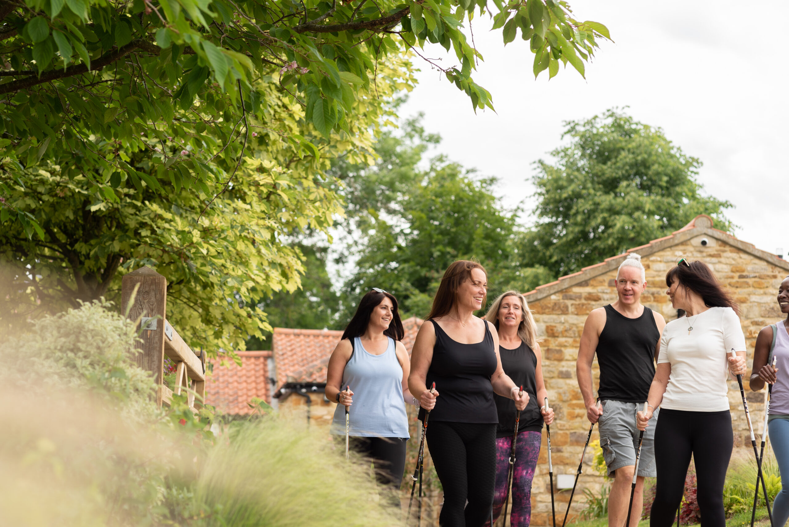 An image of individuals walking along a oath surrounded by trees and greenery. A group of people participating in an outdoor fitness activity