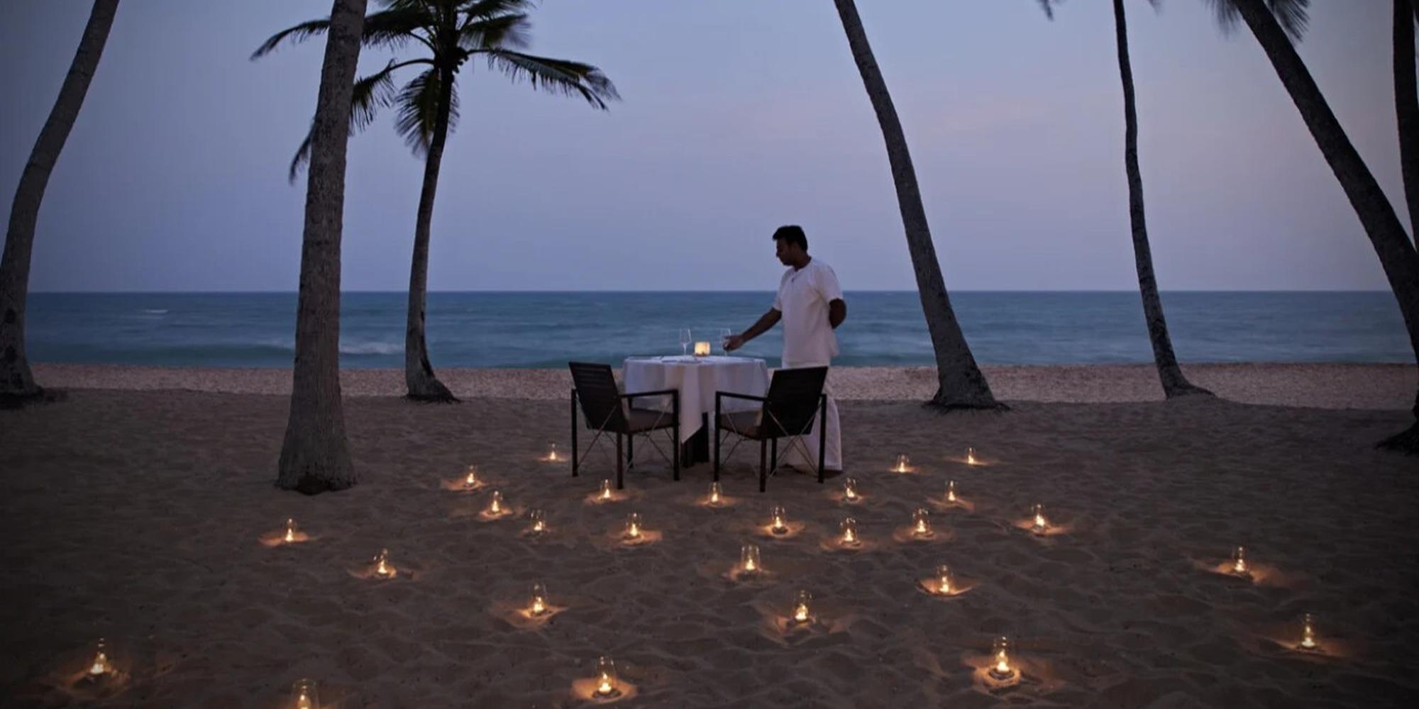 An intimate scene with candlelit dinner set on serene tropical beach near the Amanwella resort in Sri Lanka.