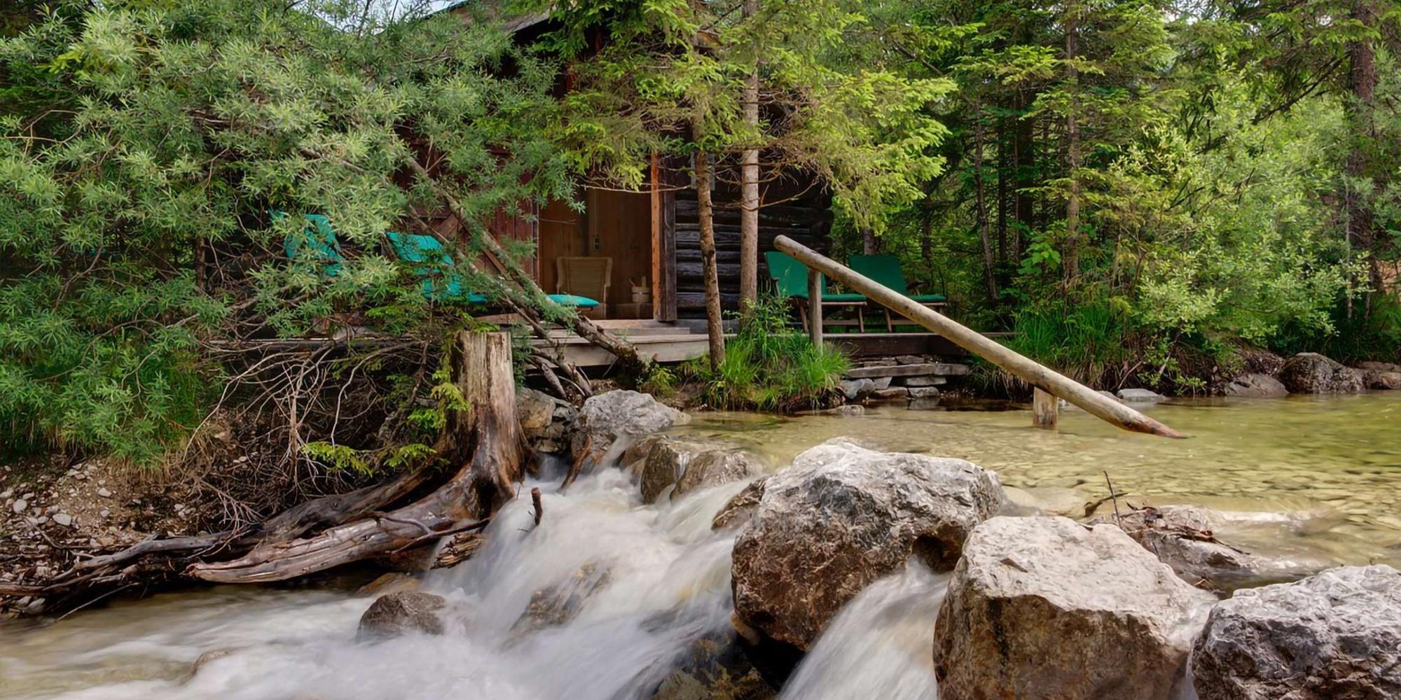 Tranquil and scenic location featuring a small structure nestled beside a flowing stream at Schloss Elmau.