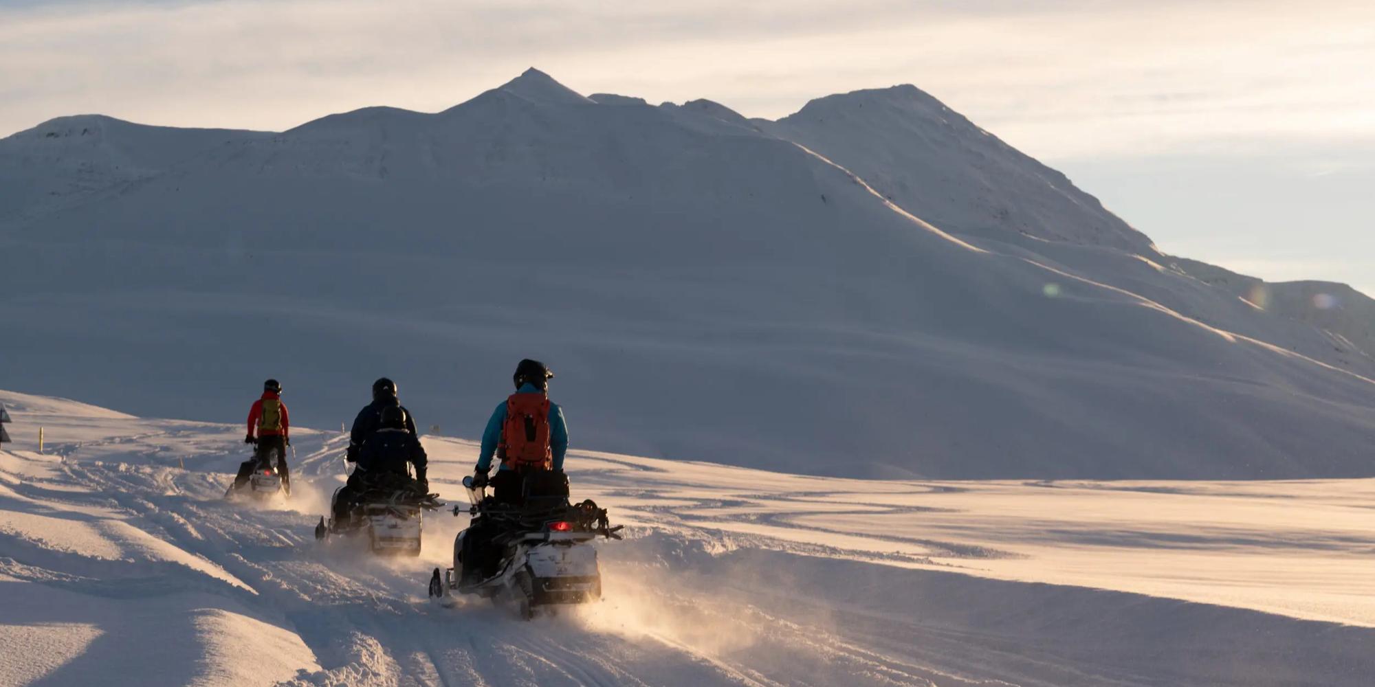 A picture of Snowmobilers traversing a snowy mountain range at Deplar Iceland. Snowmobilers traversing a snowy mountain range at Deplar Iceland.