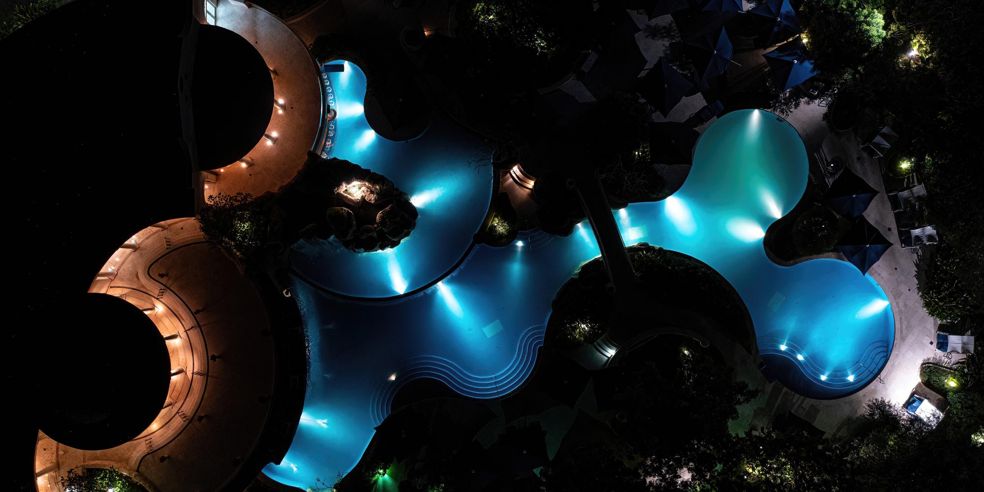 A modern, artistically designed swimming pool with vibrant blue lighting at night at the Sandy Lane in Barbados Modern, artistically designed swimming pool with vibrant blue lighting at night at the Sandy Lane in Barbados