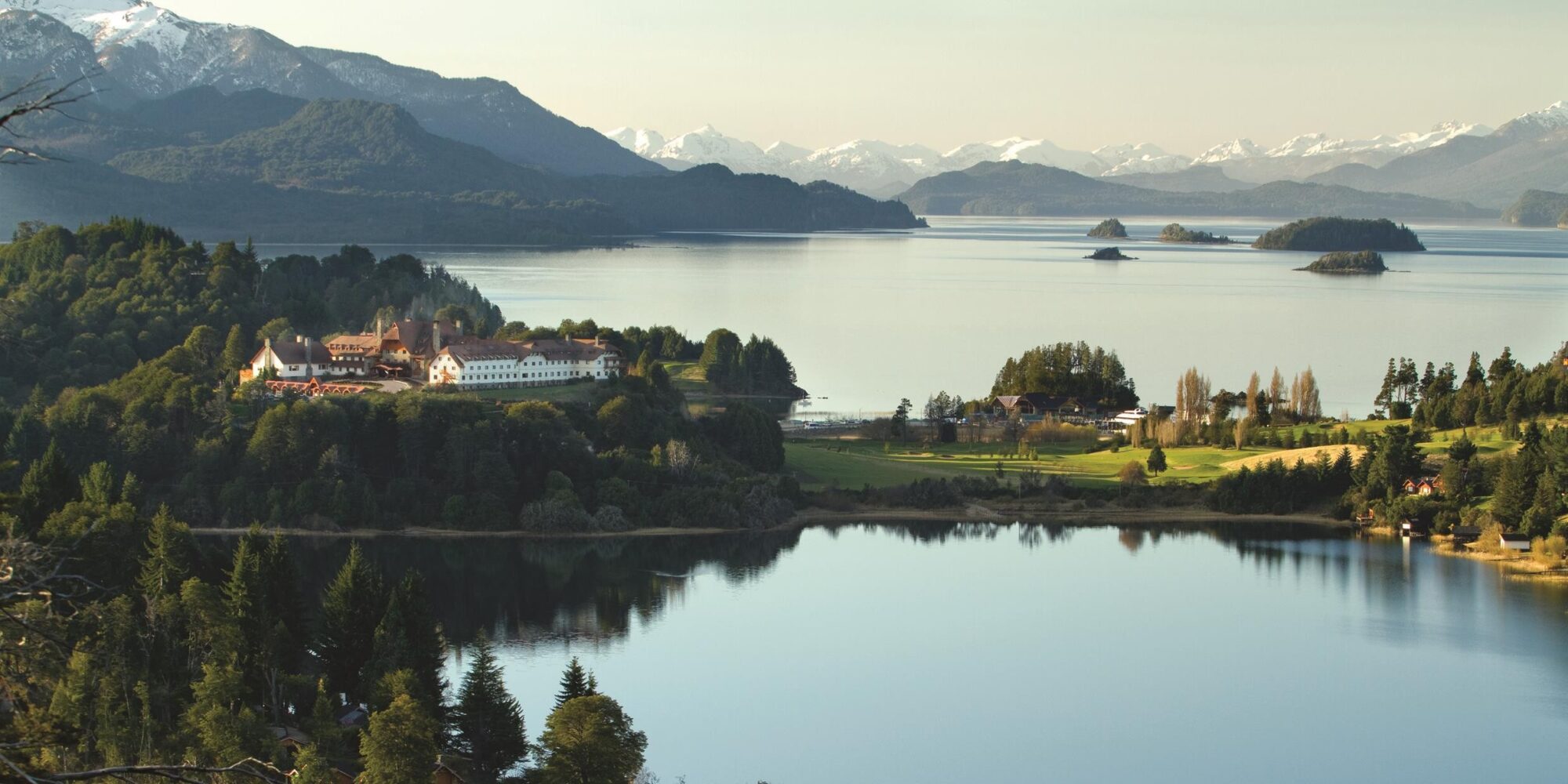 A lake nestled against large mountains featuring a white house double story in Argentina. A lake nestled against large mountains featuring a white house double story in Argentina.
