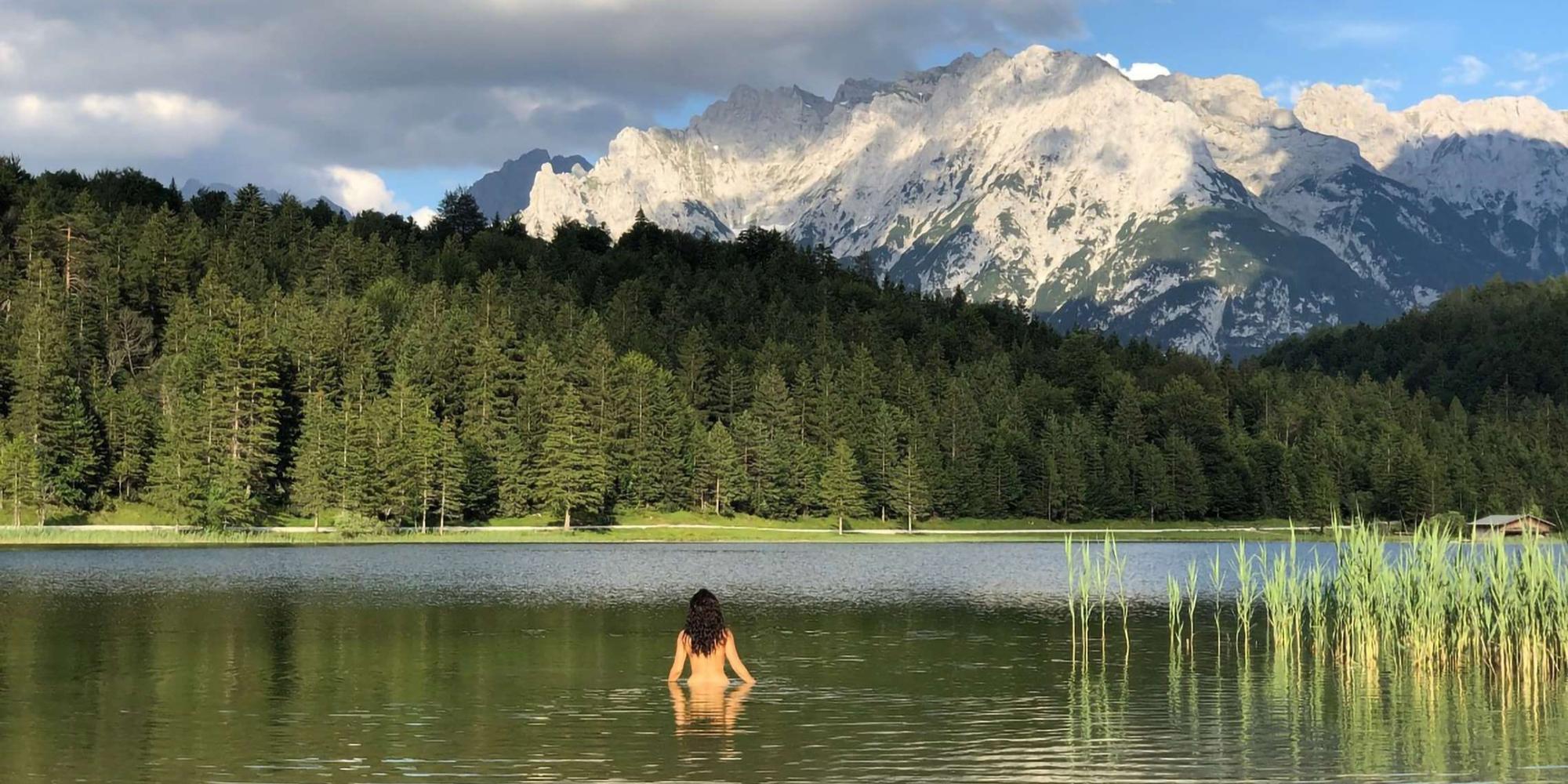 An image of lake featuring a woman inside and mountains at Schloss Elmau, Europe An image of lake featuring a woman inside and mountains at Schloss Elmau, Europe.