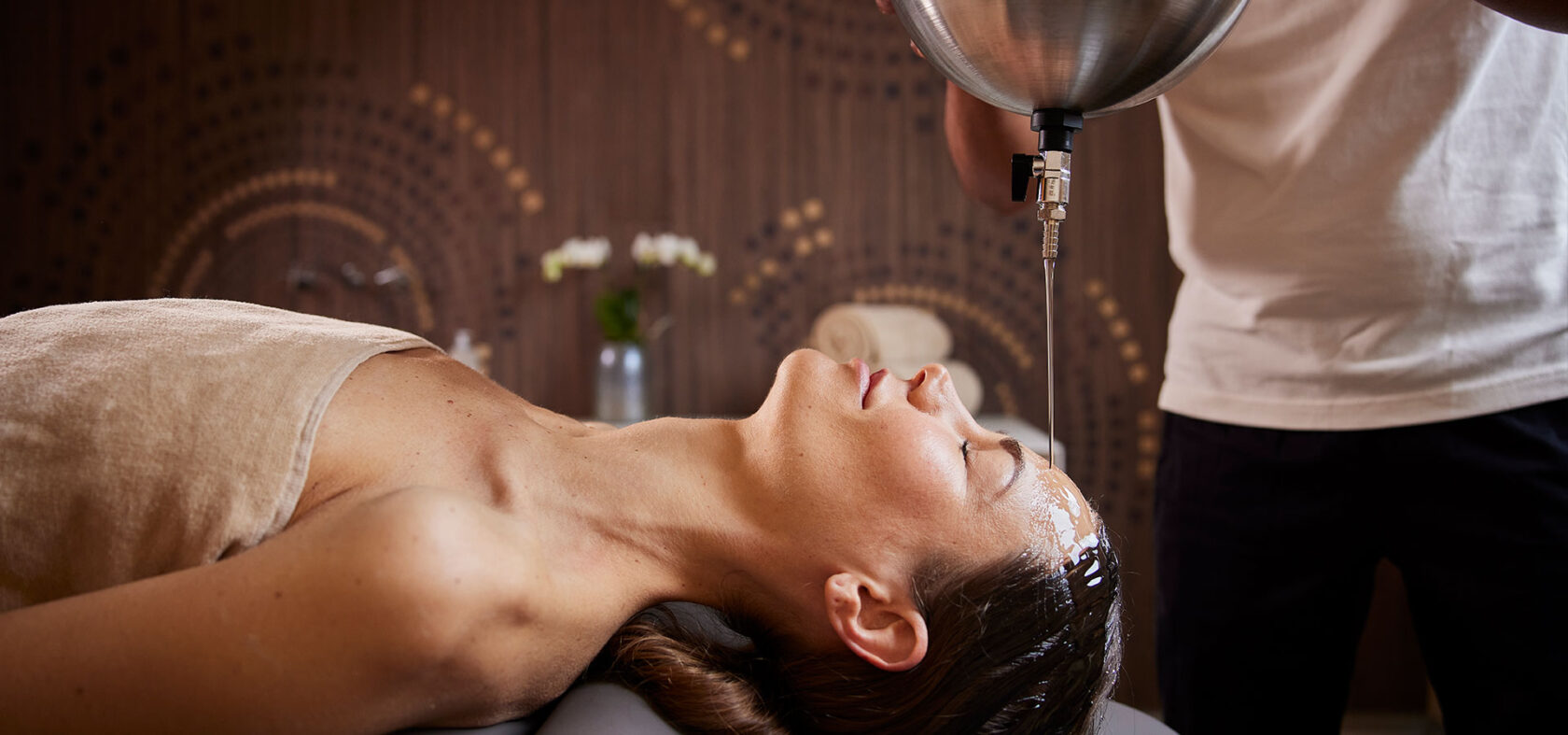 A person receiving an oil-pouring therapy at a spa.