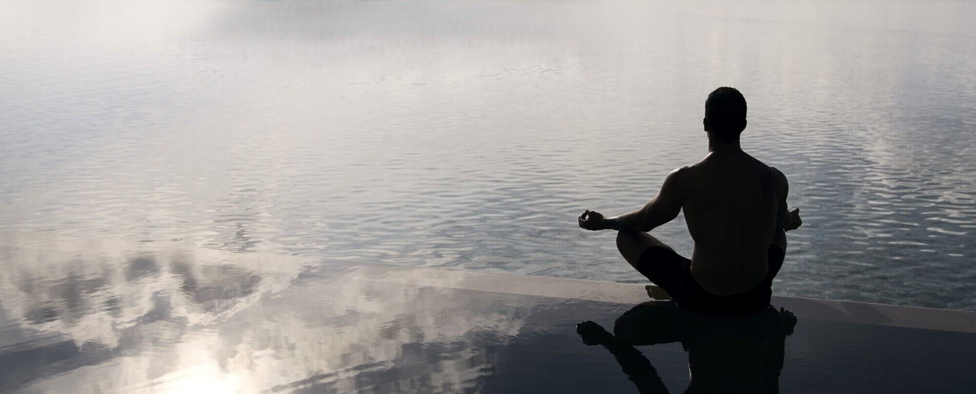 A person practising yoga near water. A person practising yoga near water.
